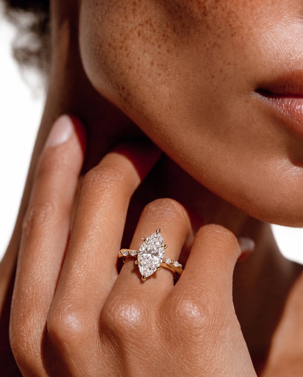 color_10K_YG, color_14K_YG &&A close-up lifestyle shot of a model wearing a yellow gold marquise-cut diamond engagement ring on her finger.