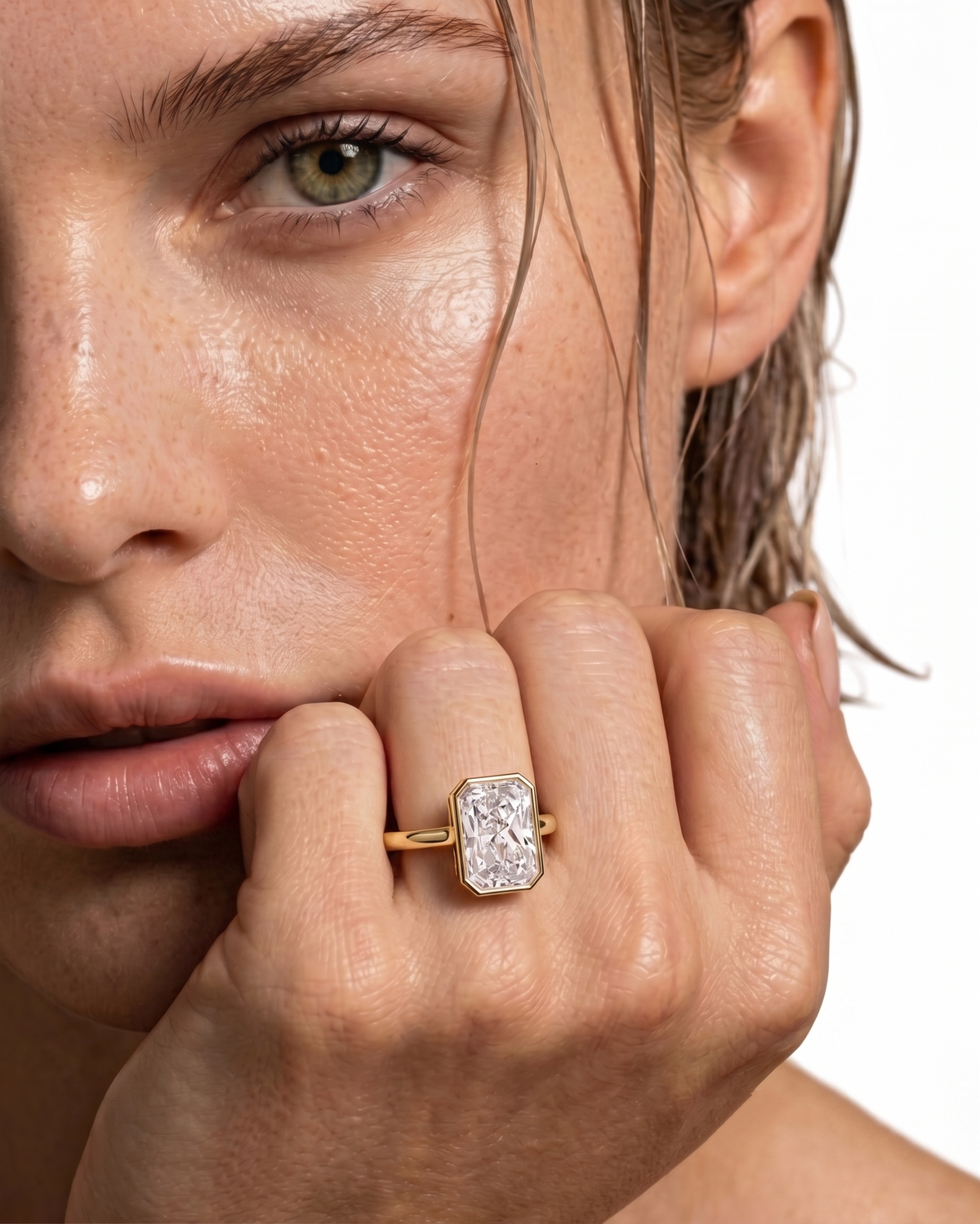 color_10K_YG, color_14K_YG &&Close-up of a model wearing a yellow gold ring with a rectangular baguette-cut clear gemstone on the ring finger, set against a clean white background.