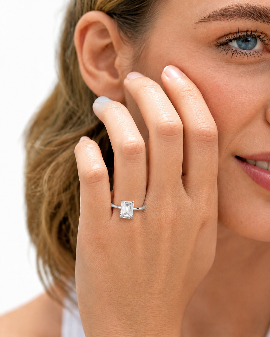 color_925_SIL,color_935_ARG,color_10K_WG, color_14K_WG &&
A close-up lifestyle shot of a woman wearing a silver ring with a rectangular clear gemstone on her finger, with her hand resting against her cheek against a white background.