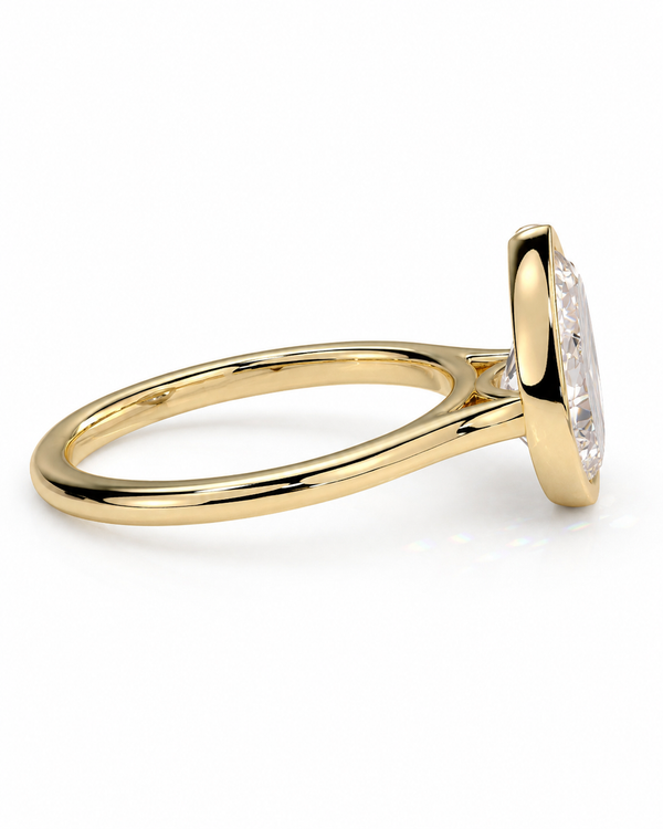 color_10K_YG, color_14K_YG &&A close-up side view of a yellow gold ring with a marquise-cut clear gemstone in a bezel setting, on a clean white background.