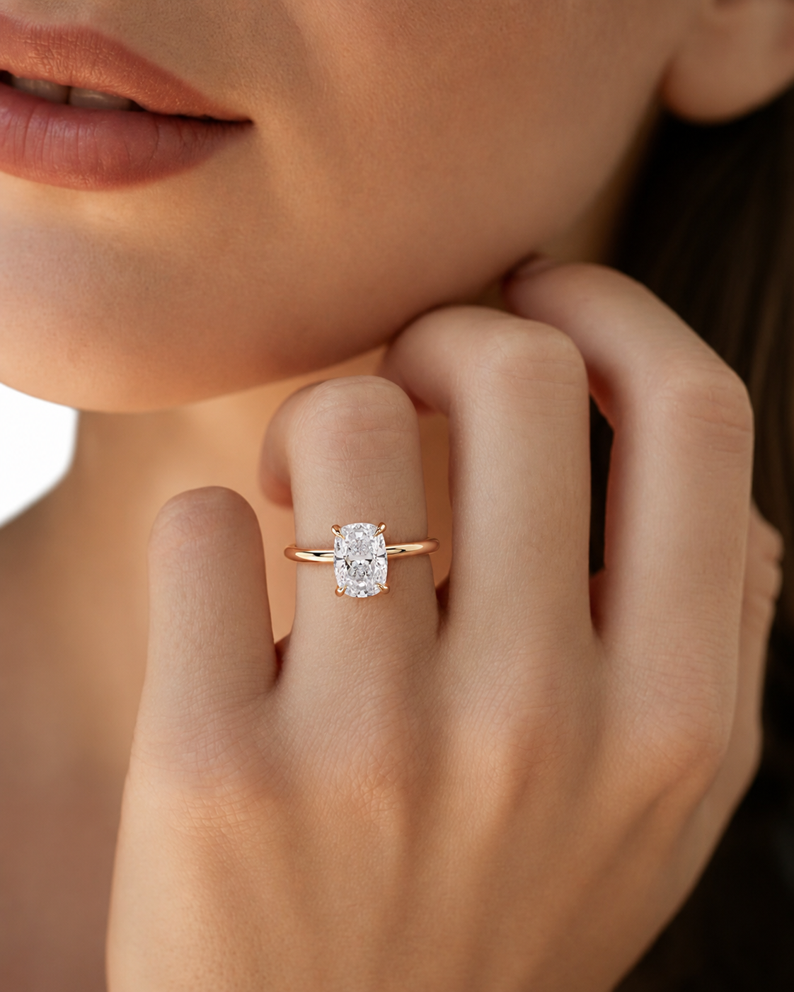 color_10K_YG, color_14K_YG &&A close-up lifestyle shot of a model wearing a rose gold ring with a rectangular clear gemstone on her finger.
