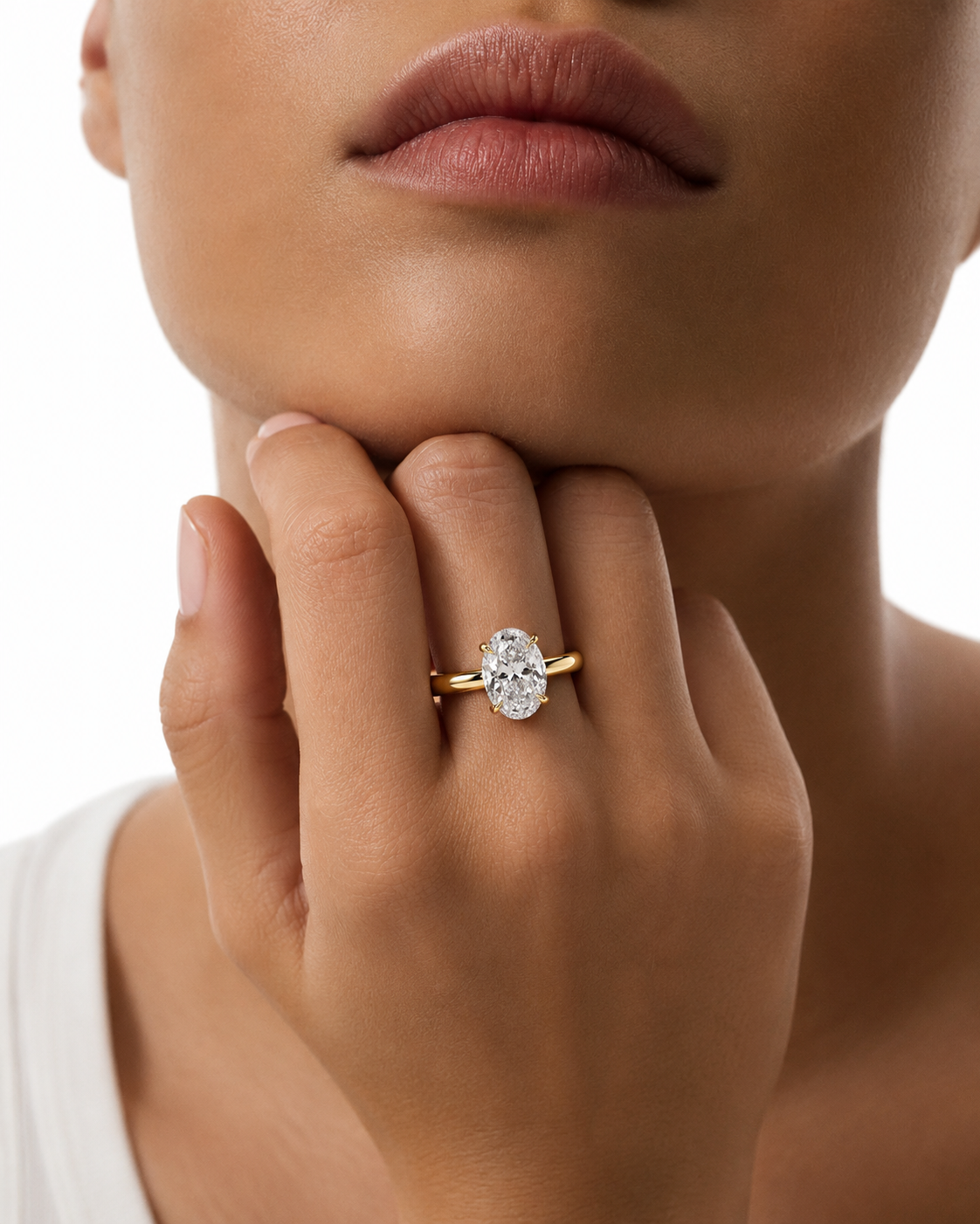 color_10K_YG, color_14K_YG &&A close-up lifestyle shot of a model wearing a yellow gold engagement ring with a round brilliant-cut diamond. The ring is shown on the model's ring finger, with her hand resting near her chin against a clean white background.