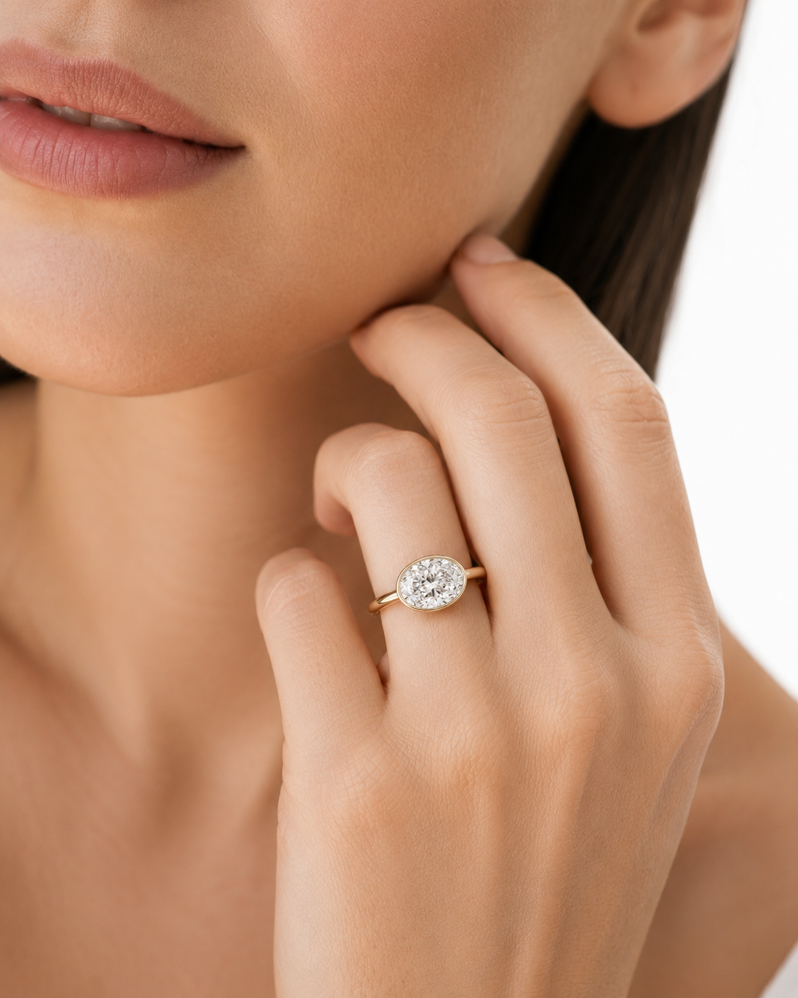 color_10K_YG, color_14K_YG &&A close-up lifestyle shot of a woman wearing a yellow gold ring with a round brilliant-cut diamond. The ring is shown on her finger, with her hand resting near her chin against a clean white background.