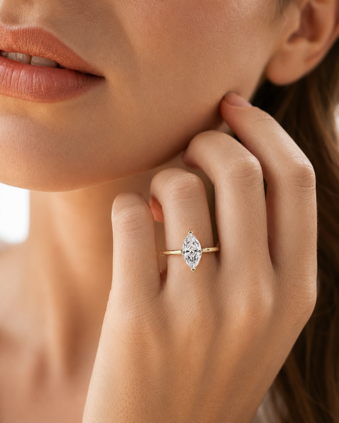 color_10K_YG, color_14K_YG &&A close-up lifestyle shot of a model wearing a gold ring with a marquise-cut clear gemstone on her finger.