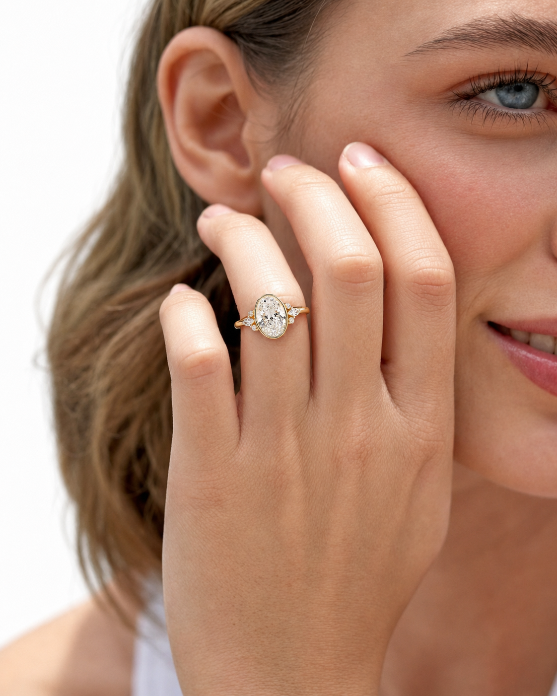 color_10K_YG, color_14K_YG &&A close-up lifestyle shot of a woman wearing a gold ring with a round-cut clear gemstone on her finger, with her hand resting against her cheek against a clean white background.