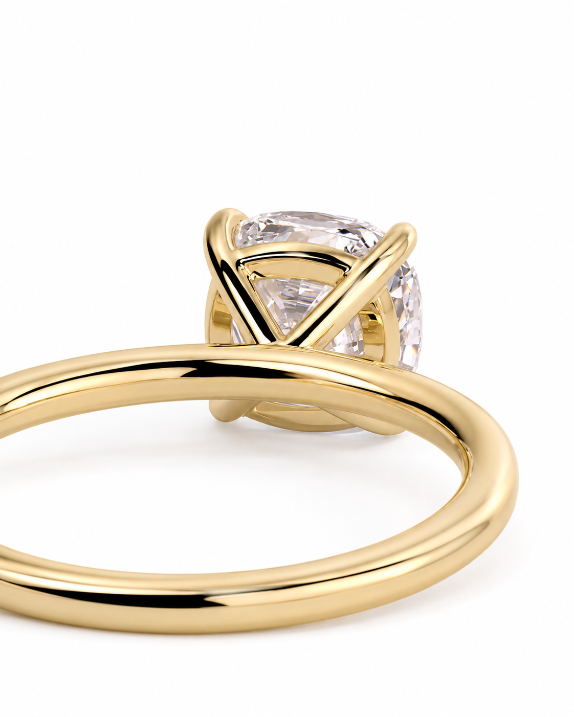 color_10K_YG, color_14K_YG &&A close-up shot of a gold ring featuring a clear cushion-cut gemstone in a unique crisscross prong setting, shown on a plain white background.