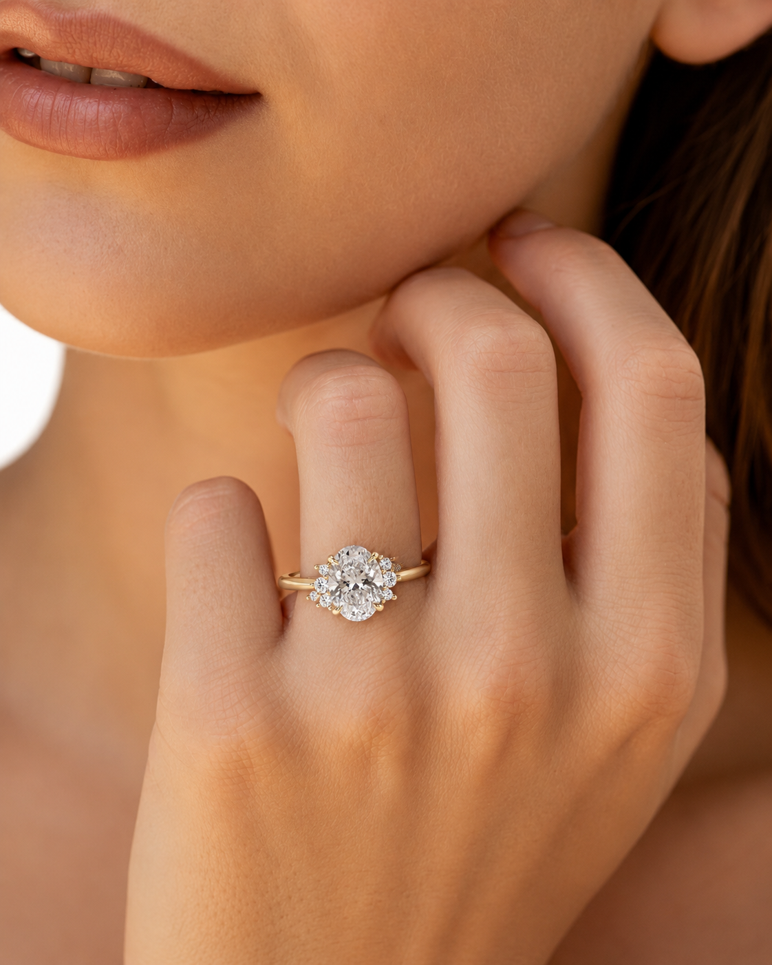 color_10K_YG, color_14K_YG &&A close-up lifestyle shot of a model's hand wearing a yellow gold ring with a round-cut diamond cluster, set against a soft, warm skin-toned background.