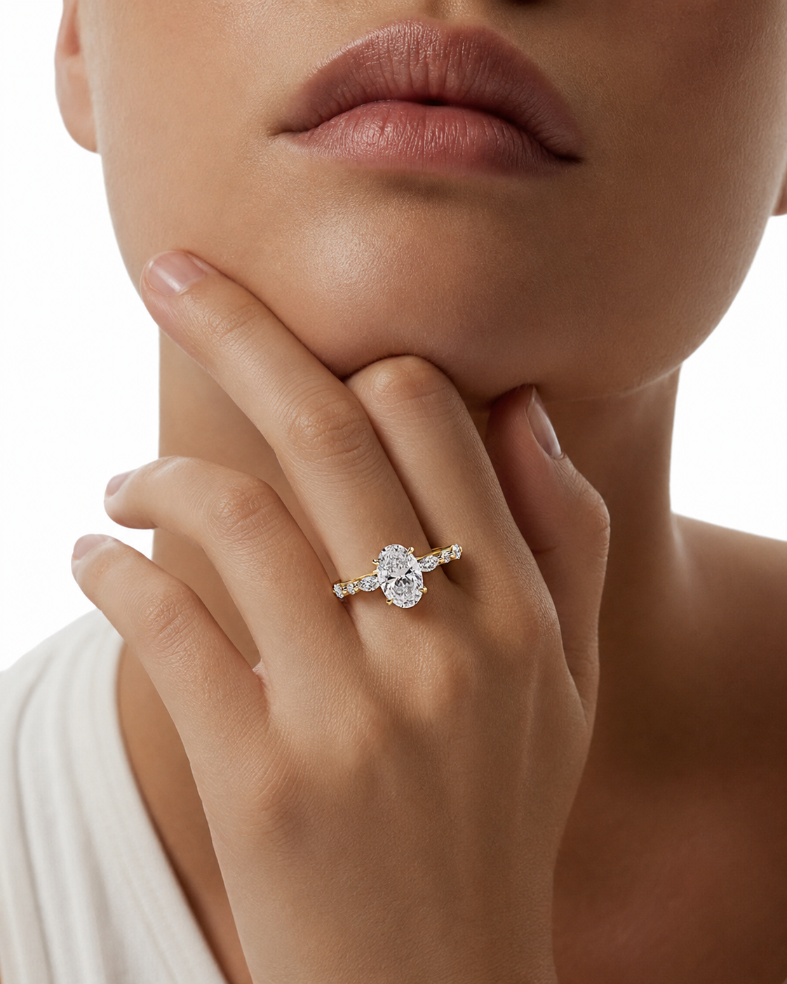 color_10K_YG, color_14K_YG &&
A close-up lifestyle shot of a model wearing a delicate yellow gold ring with a pear-cut clear center stone and small side stones, resting on her index finger.