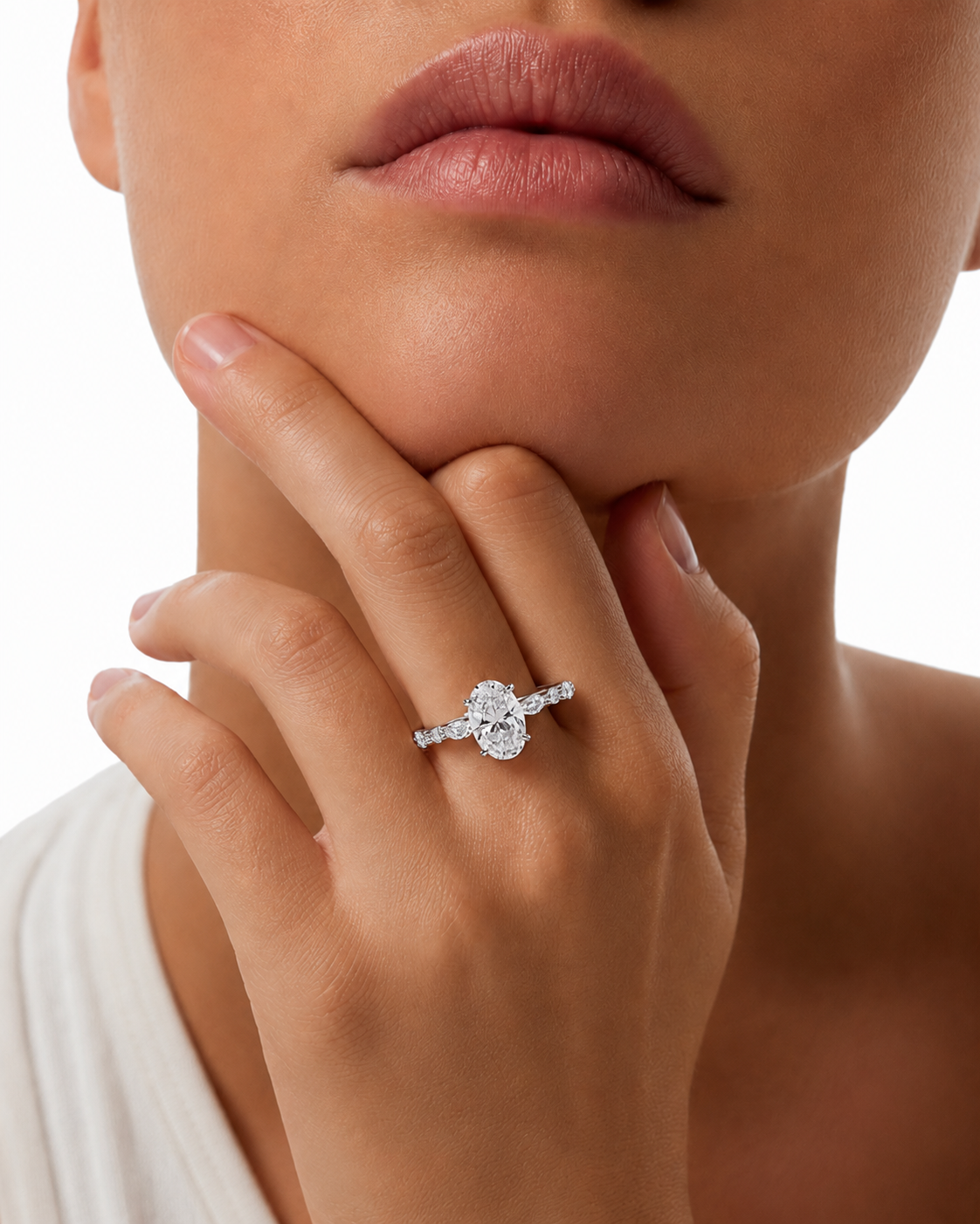 color_925_SIL,color_935_ARG,color_10K_WG, color_14K_WG &&
A close-up lifestyle shot of a model wearing a silver ring with a central round-cut clear gemstone and smaller side stones, resting on her finger near her chin.