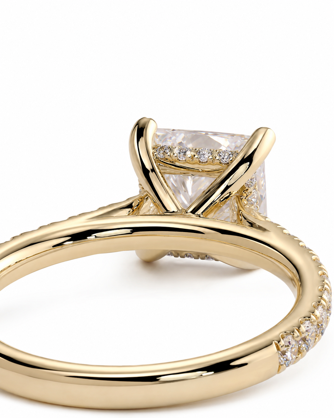 color_10K_YG, color_14K_YG &&A close-up shot of a yellow gold ring featuring a square princess-cut clear gemstone in a four-prong setting, with small pavé diamonds along the shank, on a white background.