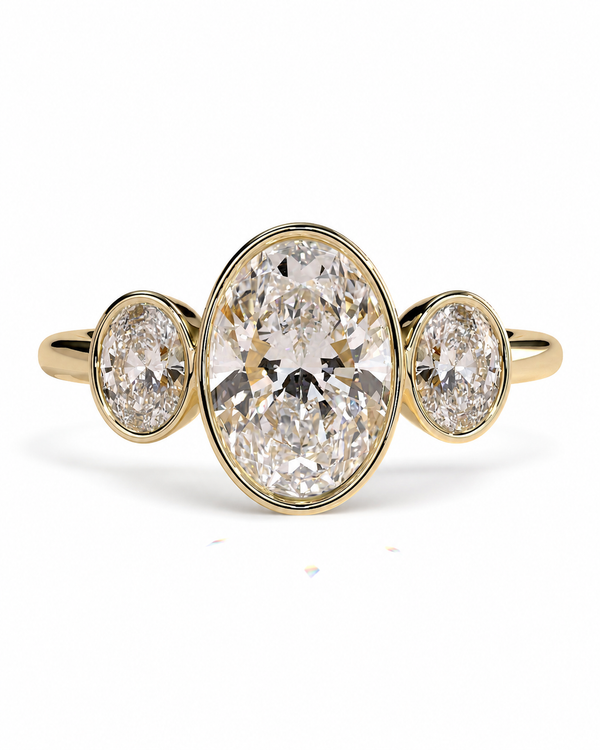 color_10K_YG, color_14K_YG &&A yellow gold three-stone ring featuring a large oval center diamond flanked by two smaller oval side diamonds, set against a clean white background.
