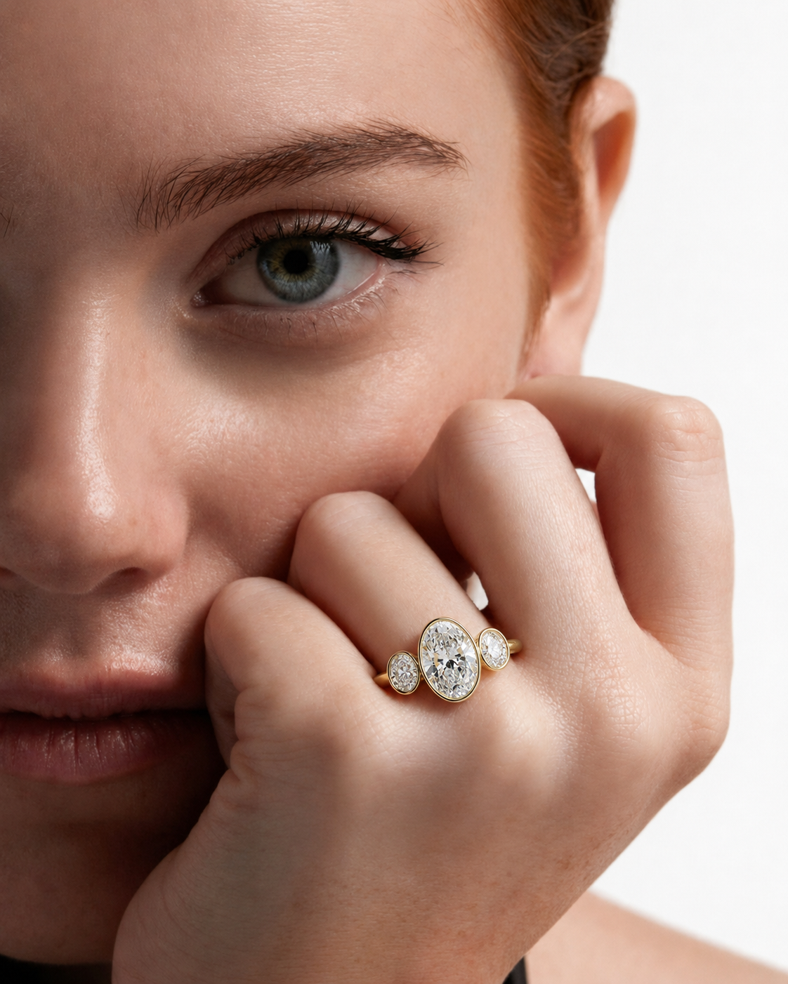 color_10K_YG, color_14K_YG &&A close-up lifestyle shot of a model wearing a gold ring with a round bezel-set cluster of clear gemstones on her finger, with her hand resting near her face against a clean white background.