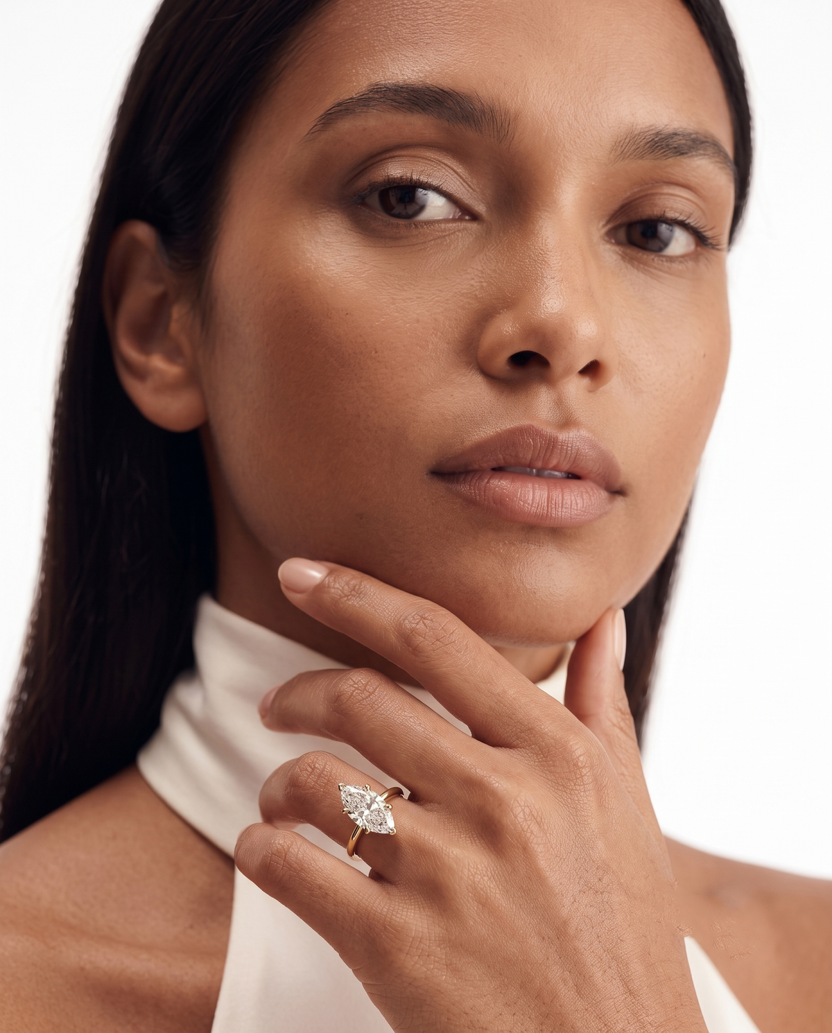 color_10K_YG, color_14K_YG &&A close-up portrait of a woman wearing a delicate gold ring with a marquise-cut clear gemstone on her finger, set against a clean white background.