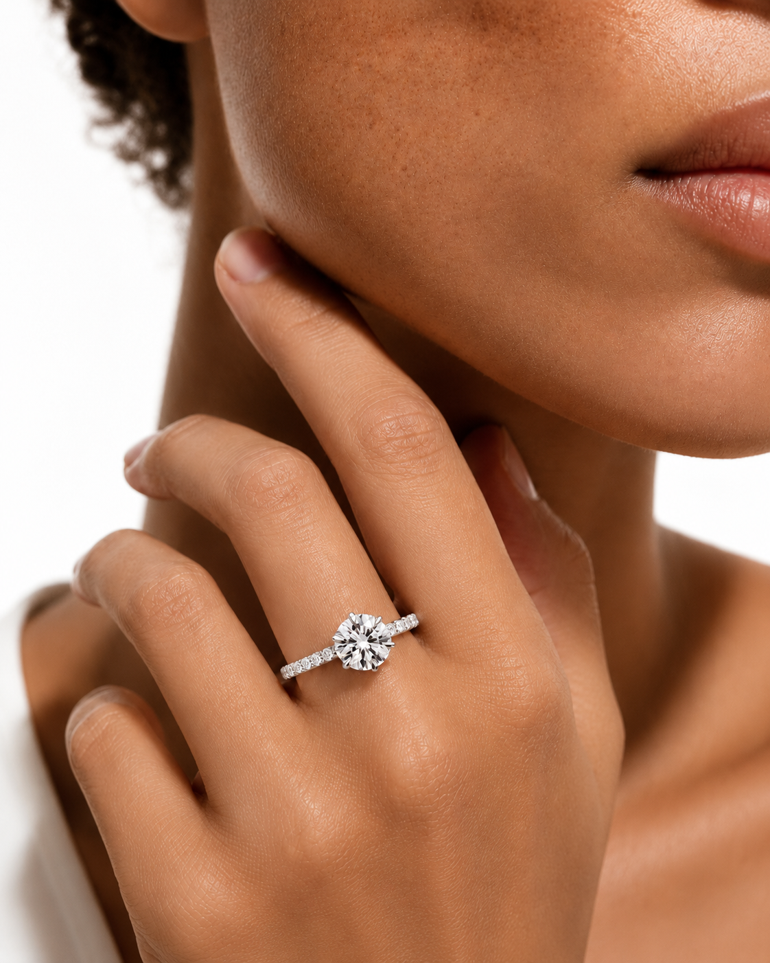 color_925_SIL,color_935_ARG,color_10K_WG, color_14K_WG &&
A close-up lifestyle shot of a model wearing a silver-toned diamond ring with a floral center and pave band, resting her hand on her chin against a clean white background.