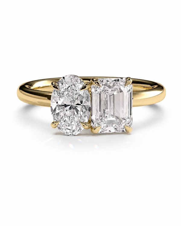 color_10K_YG, color_14K_YG &&A yellow gold ring featuring an oval-cut diamond on the left and an emerald-cut diamond on the right, set on a polished gold band against a white background.