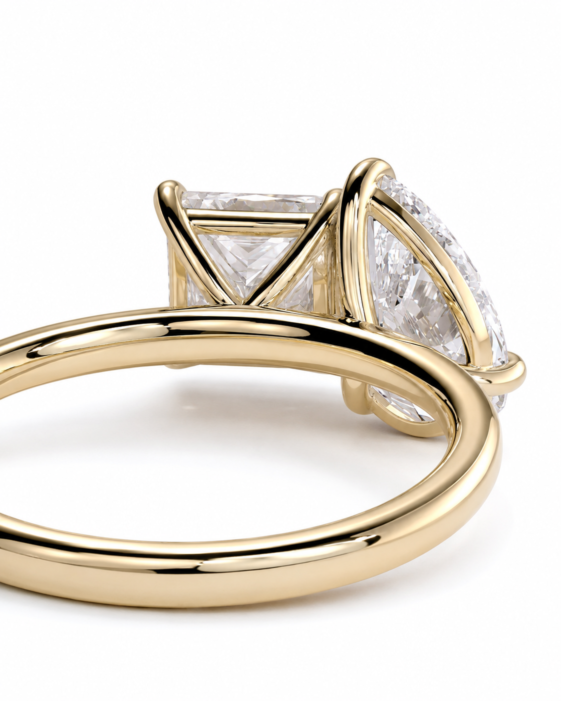 color_10K_YG, color_14K_YG &&A close-up shot of a yellow gold ring with a large cushion-cut diamond and smaller side diamonds in a four-prong setting, on a white background.