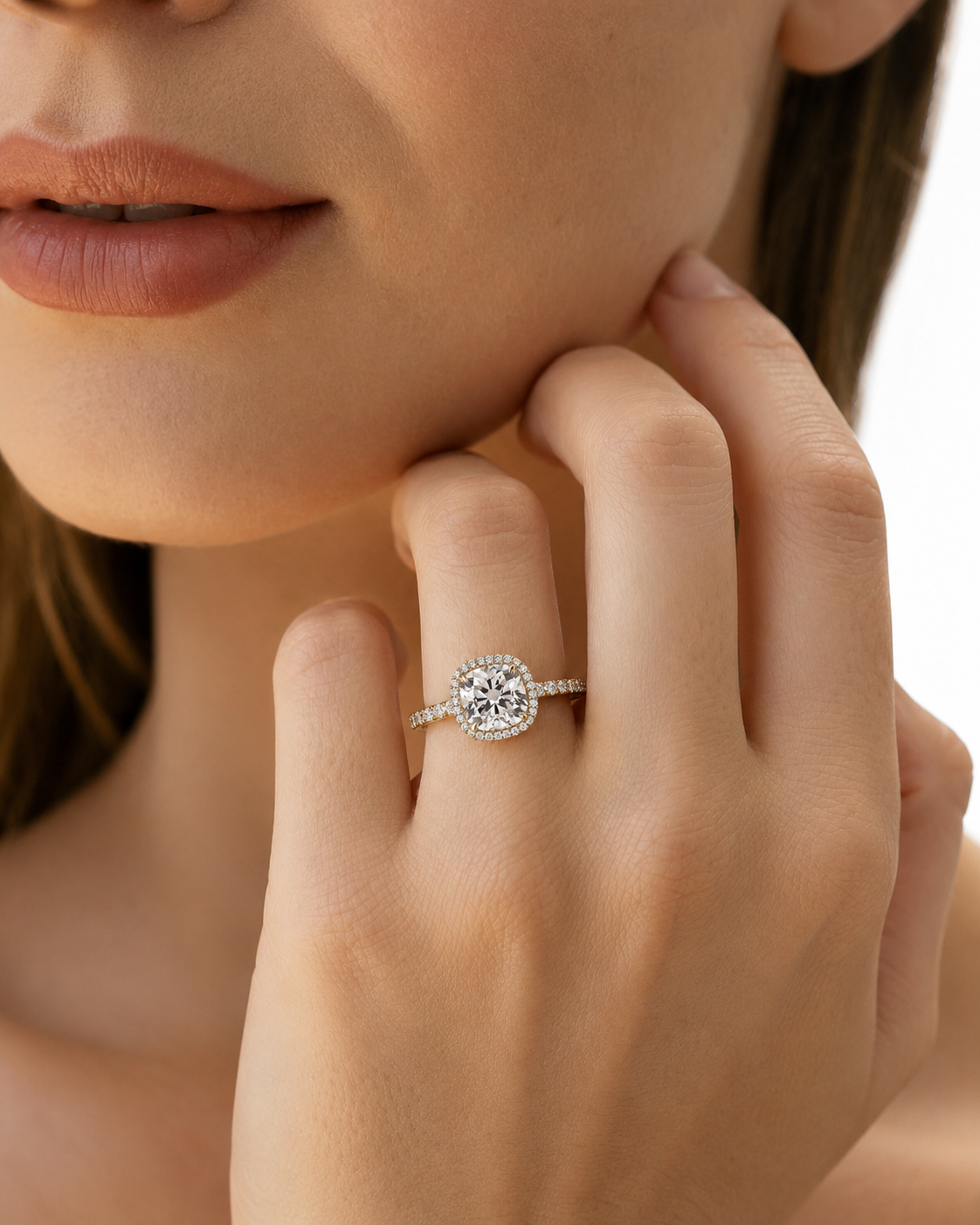 color_10K_YG, color_14K_YG &&A close-up lifestyle shot of a woman wearing a diamond engagement ring on her finger, with her hand resting near her chin against a clean white background.