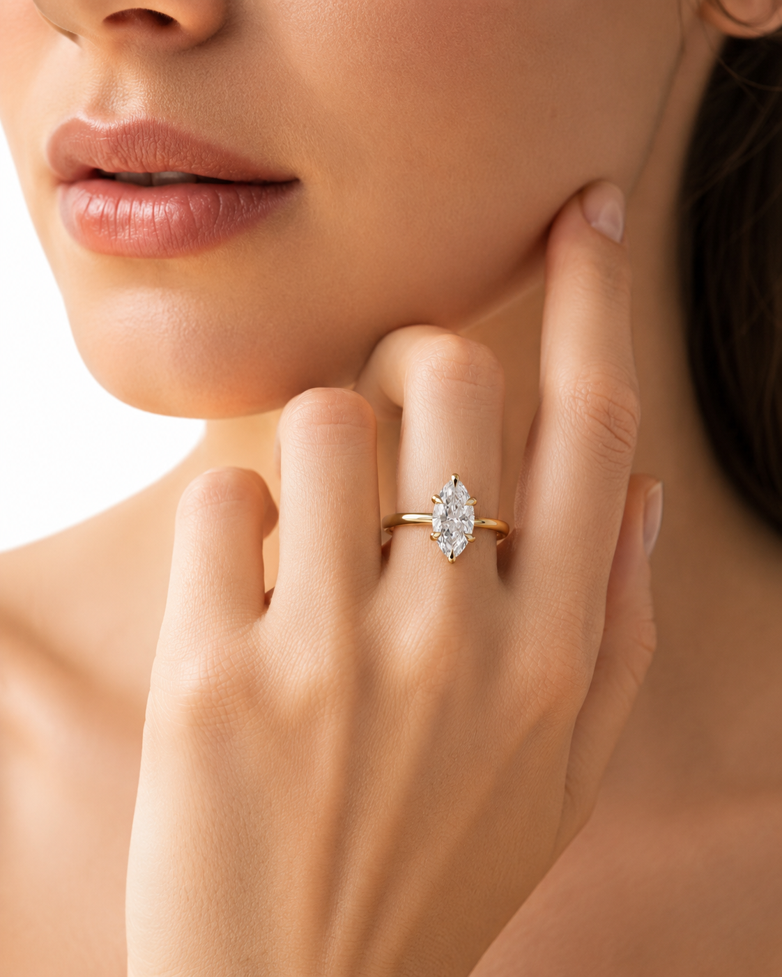 color_10K_YG, color_14K_YG &&A close-up lifestyle shot of a model wearing a gold ring with a marquise-cut clear gemstone on her finger.
