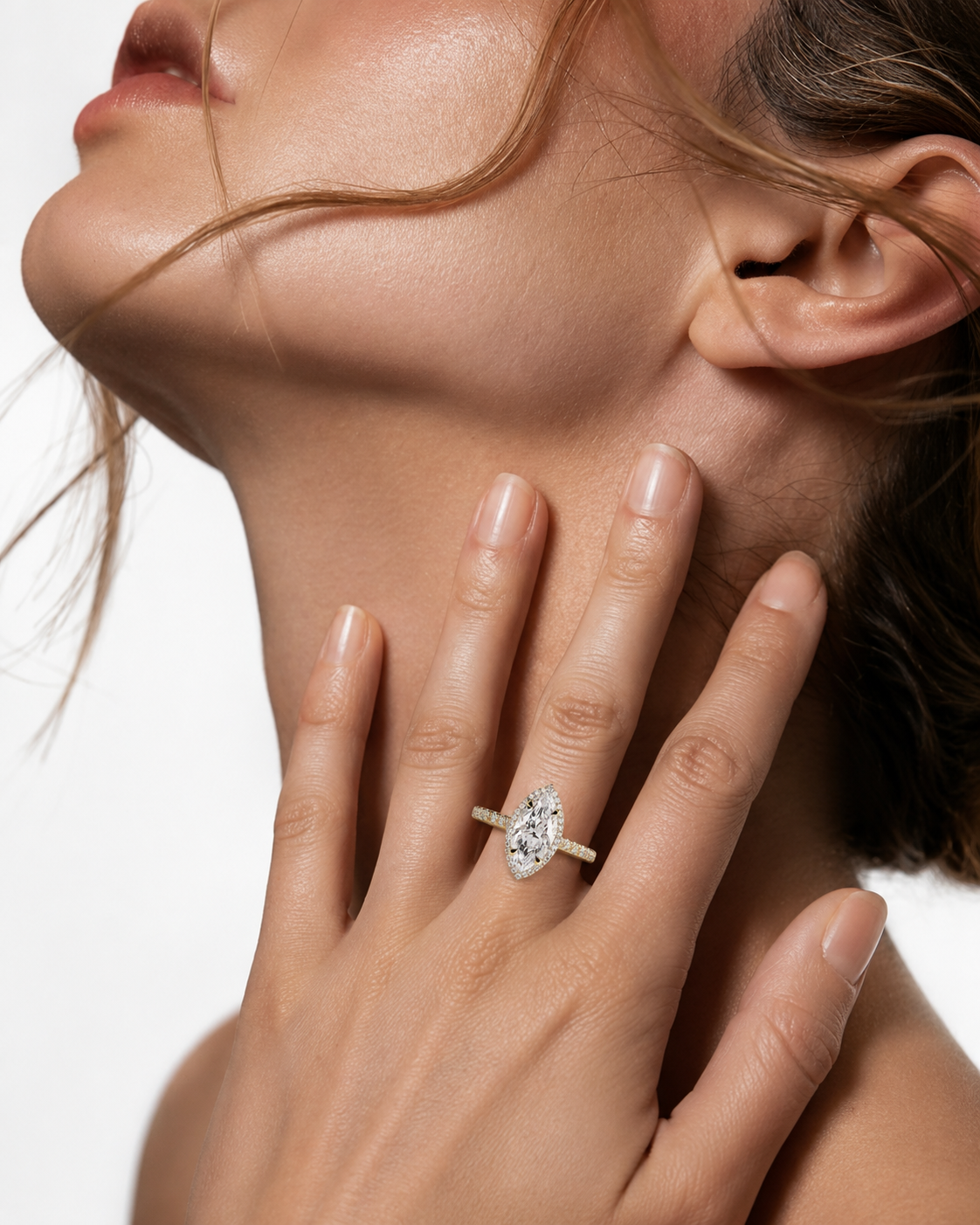 color_10K_YG, color_14K_YG &&A close-up lifestyle shot of a model wearing a silver ring with a marquise-cut diamond on her finger, with her hand resting on her neck against a clean white background.