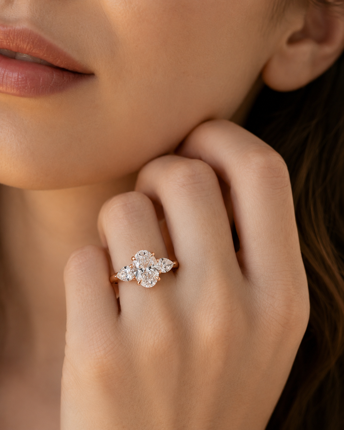 color_10K_RG, color_14K_RG &&
A close-up lifestyle shot of a model's hand wearing a rose gold ring with a floral cluster of clear gemstones.