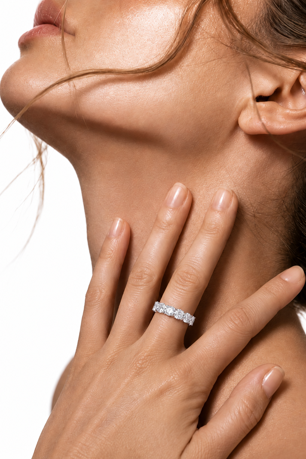 color_925_SIL,color_935_ARG,color_10K_WG, color_14K_WG &&	
A close-up lifestyle shot of a model wearing a sparkling diamond eternity ring on her finger, with her hand resting on her neck against a clean white background.