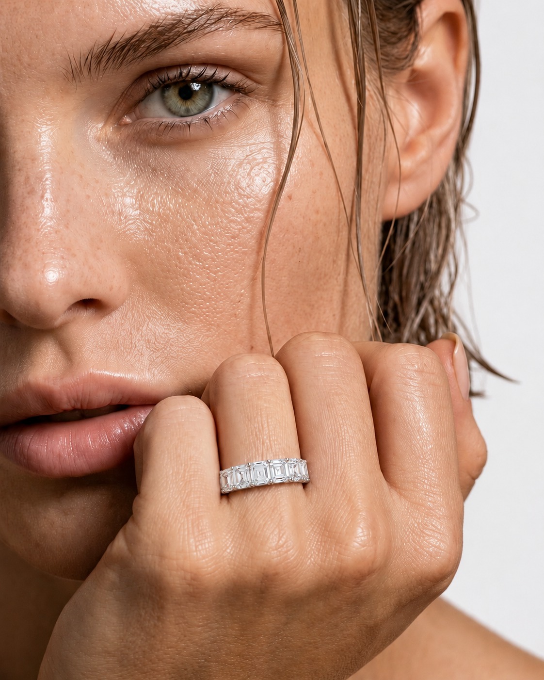 color_925_SIL,color_935_ARG,color_10K_WG, color_14K_WG &&	
A close-up lifestyle shot of a model wearing a silver band ring with a row of clear baguette-cut gemstones. The model's face and hand are shown against a clean, light gray background.