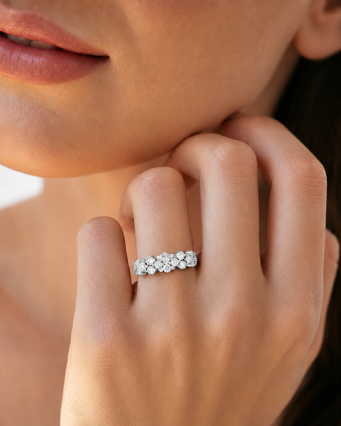color_925_SIL,color_935_ARG,color_10K_WG, color_14K_WG &&	
A close-up lifestyle shot of a woman wearing a silver band ring with a row of sparkling clear gemstones on her finger.