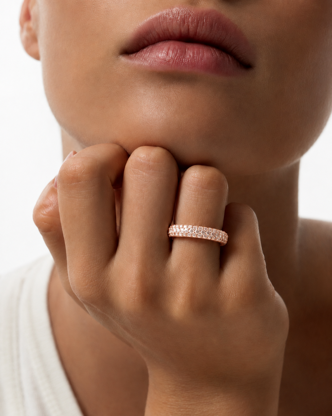 color_10K_RG, color_14K_RG &&	A close-up lifestyle shot of a model wearing a rose gold eternity ring set with small clear stones on her finger.