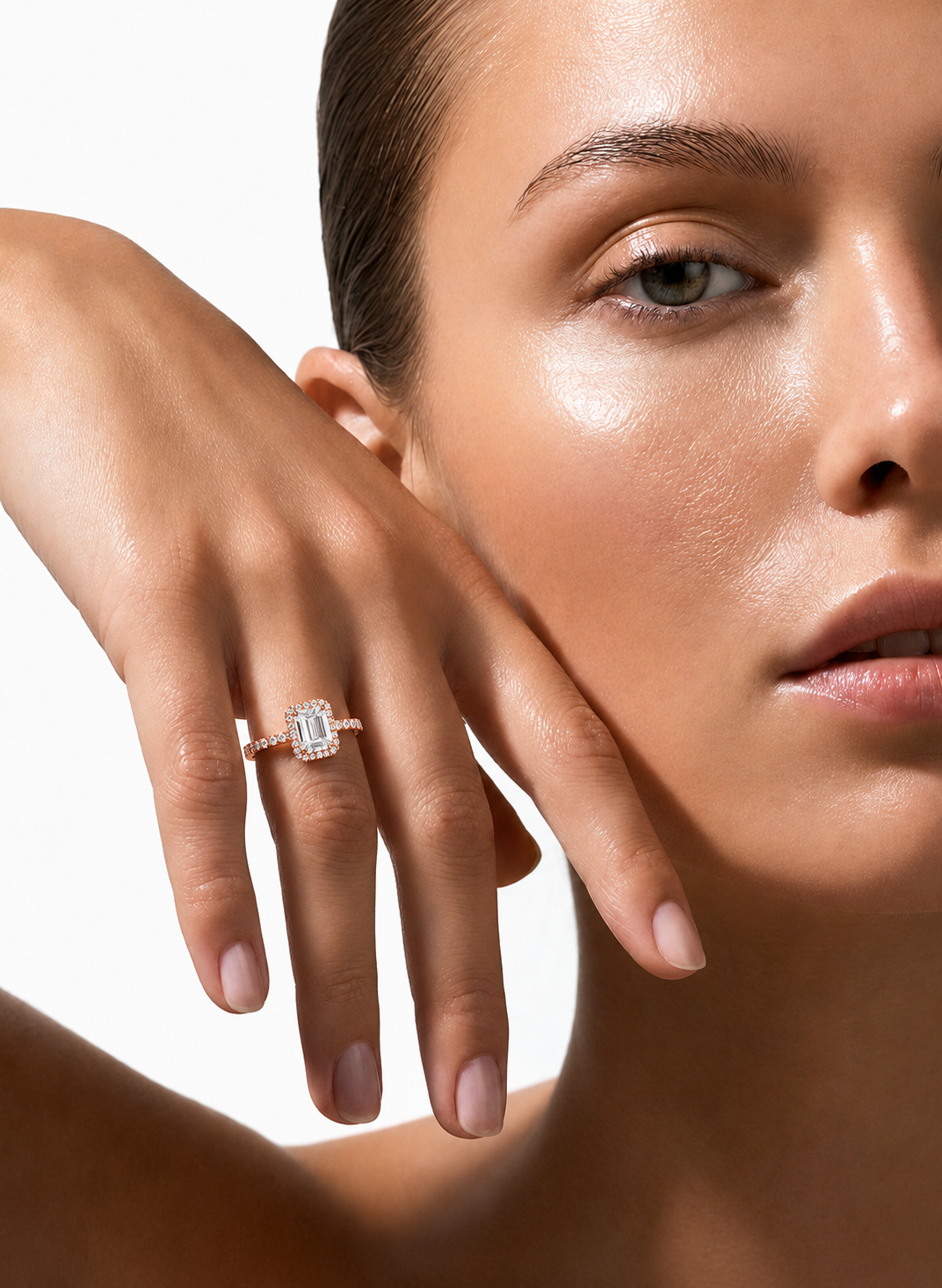 color_10K_RG, color_14K_RG &&A close-up lifestyle shot of a model wearing a rose gold ring with a rectangular baguette-cut diamond. The model's face and hand are beautifully lit against a clean white background.