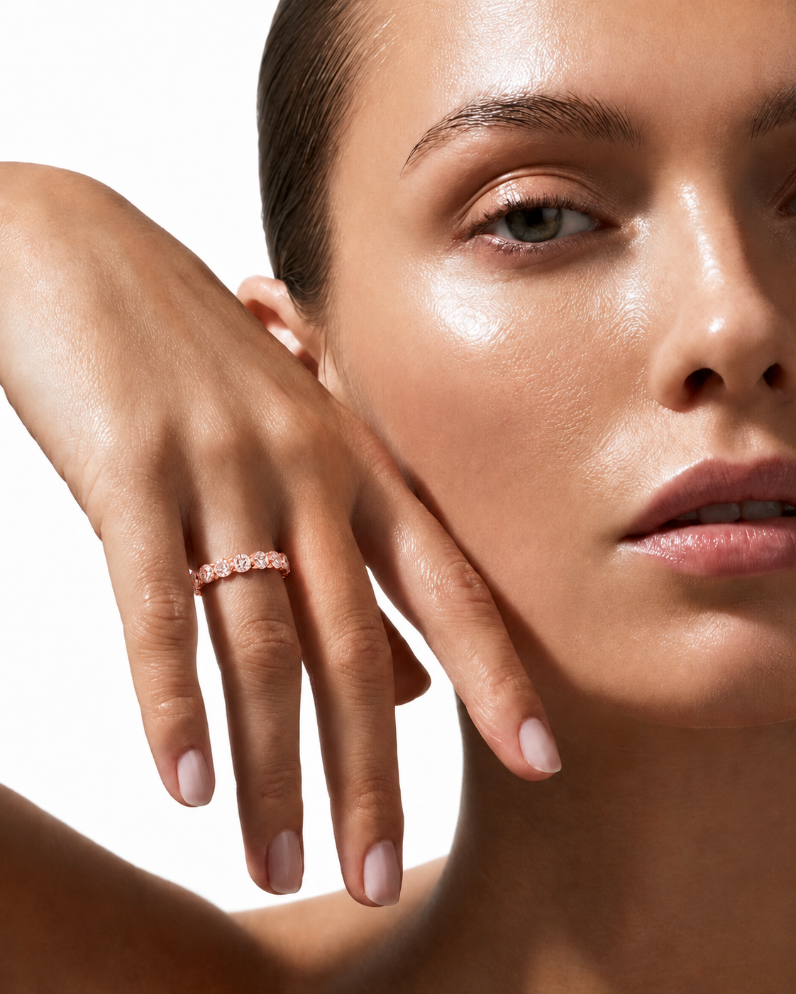 color_10K_RG, color_14K_RG &&	A close-up lifestyle shot of a model wearing a delicate rose gold band ring with small clear stones, set against a clean white background.