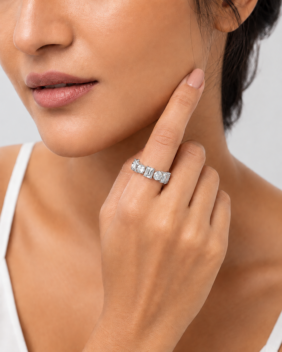 color_925_SIL,color_935_ARG,color_10K_WG, color_14K_WG &&	
A close-up lifestyle shot of a woman wearing a silver band ring with a row of clear baguette-cut gemstones on her finger.