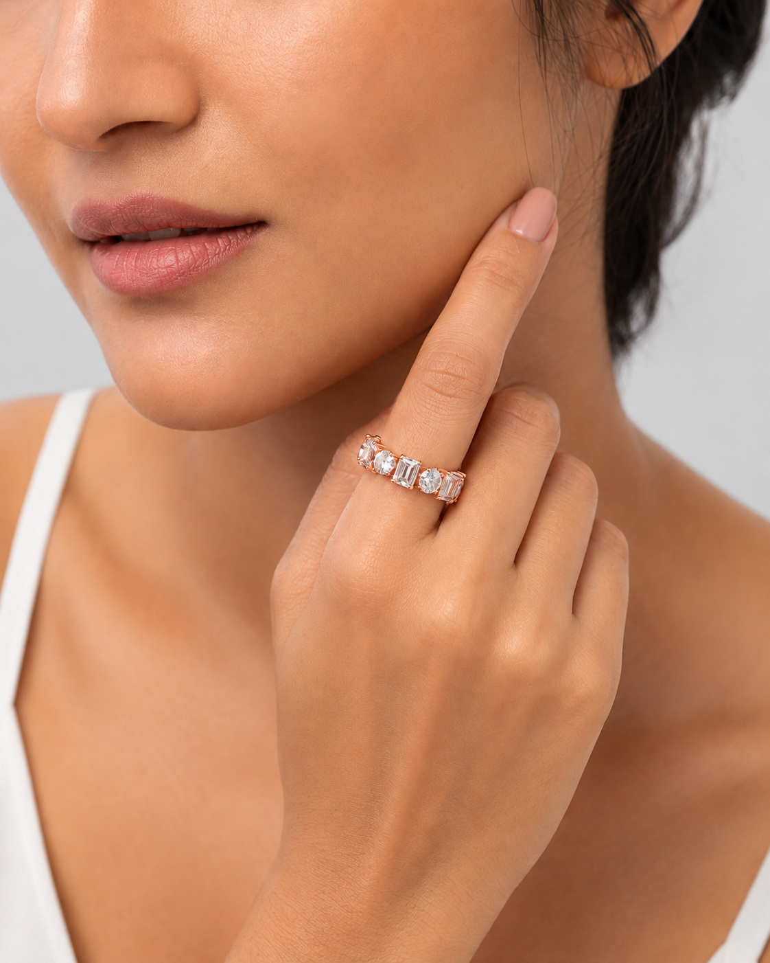 color_10K_RG, color_14K_RG &&	A close-up lifestyle shot of a model wearing a delicate silver ring with a row of clear cubic zirconia stones on her finger. The model is wearing a white top against a clean, light gray background.