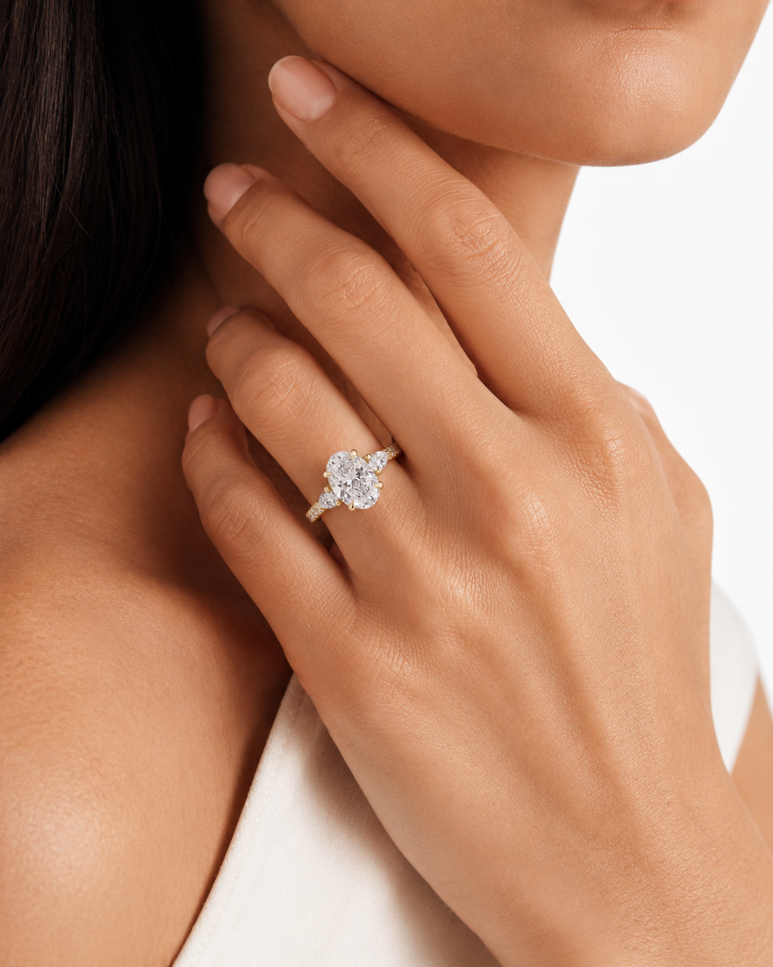 color_10K_YG, color_14K_YG &&A close-up lifestyle shot of a model wearing a diamond engagement ring with a halo setting on her finger, against a clean white background.