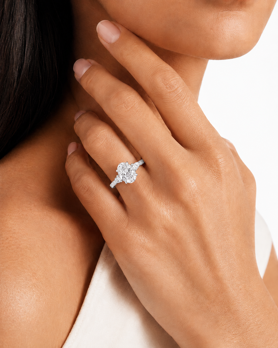 color_925_SIL,color_935_ARG,color_10K_WG, color_14K_WG &&A close-up lifestyle shot of a model wearing a sparkling diamond ring on her finger, with her hand resting near her face against a clean white background.