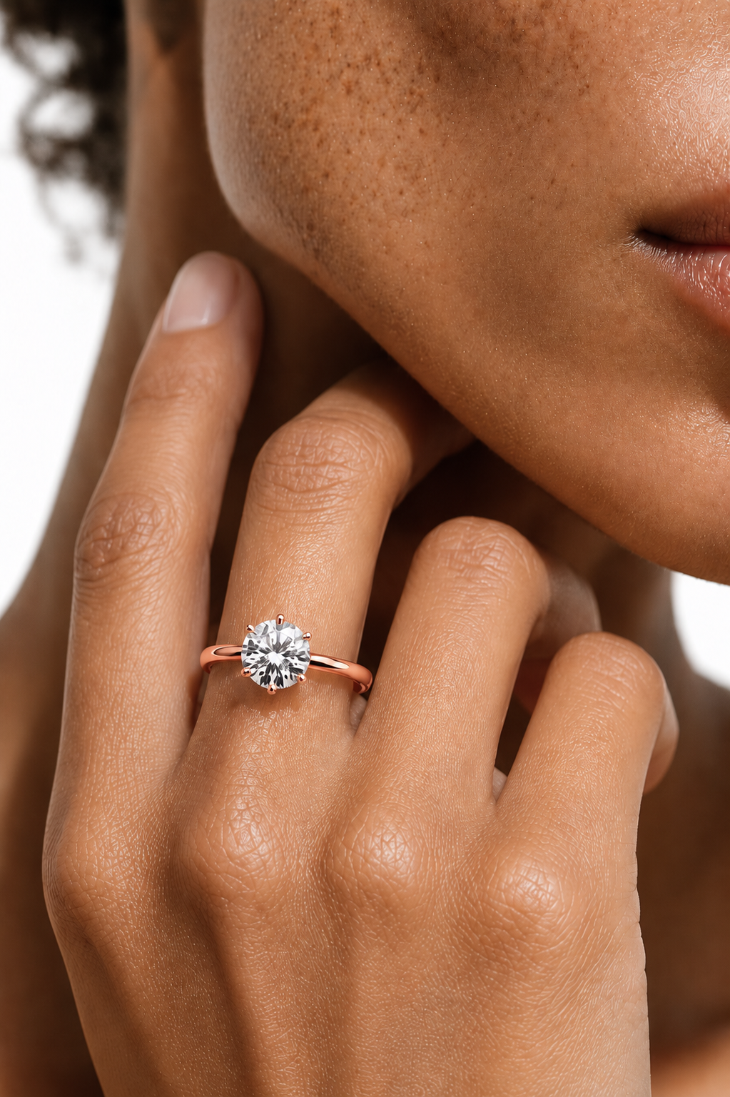 color_10K_RG, color_14K_RG &&A close-up of a model's hand wearing a yellow gold solitaire engagement ring with a round brilliant-cut diamond, set against a clean white background.