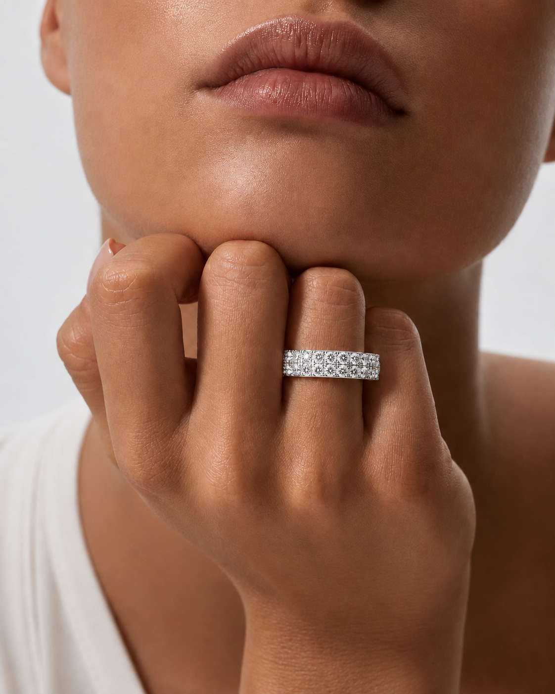 color_925_SIL,color_935_ARG,color_10K_WG, color_14K_WG &&	
A close-up of a model's hand and lower face wearing a silver band ring set with small clear stones.