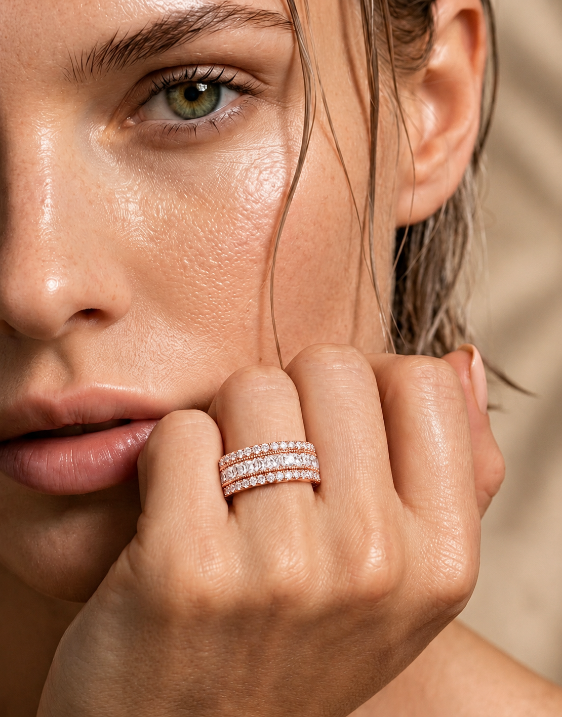 color_10K_RG, color_14K_RG &&	A close-up lifestyle shot of a model wearing a double-row diamond eternity ring in rose gold on her ring finger, set against a soft beige background.