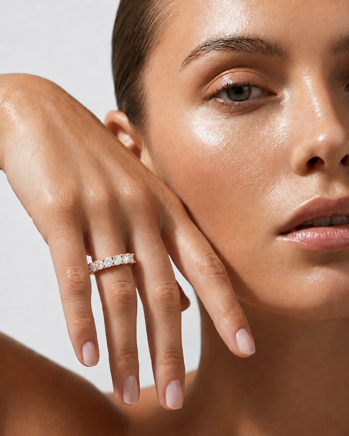 color_10K_RG, color_14K_RG &&	A close-up lifestyle shot of a model wearing a delicate diamond ring on her finger, with her hand resting against her cheek against a clean, light gray background.