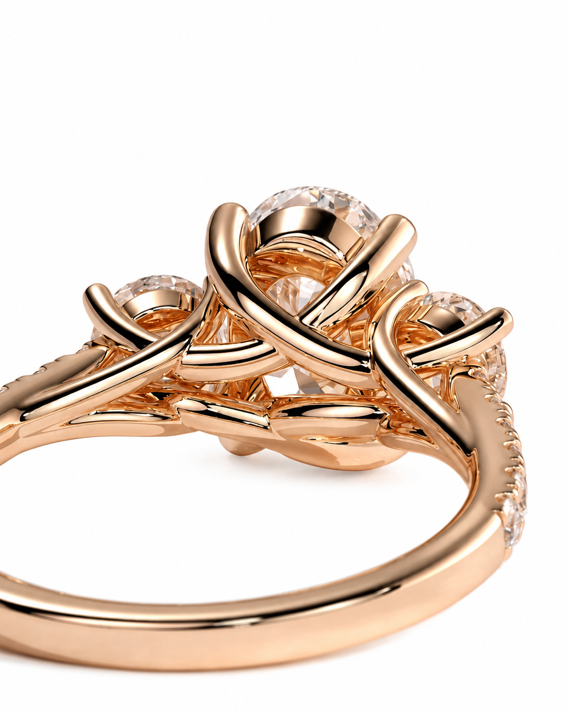 color_10K_RG, color_14K_RG &&A close-up of a rose gold ring featuring a central round clear gemstone surrounded by three smaller round clear gemstones, set in an intricate twisted band design.