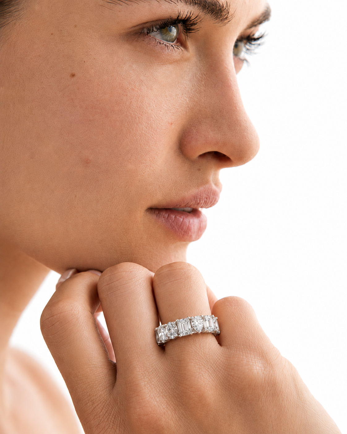 color_925_SIL,color_935_ARG,color_10K_WG, color_14K_WG &&	
A close-up side profile of a woman wearing a silver diamond eternity ring on her finger, with her hand resting near her chin against a bright white background.