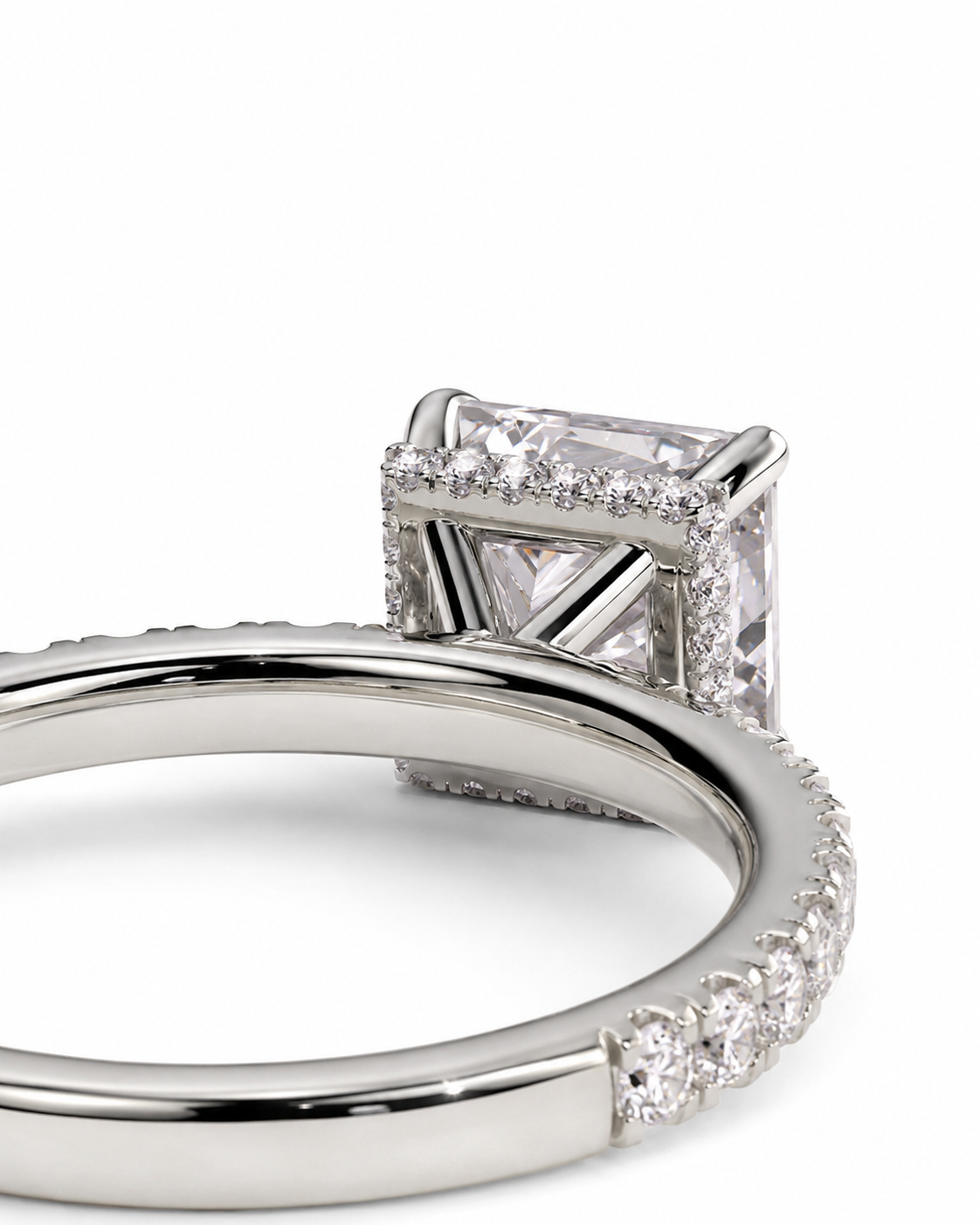 color_925_SIL,color_935_ARG,color_10K_WG, color_14K_WG &&A close-up studio shot of a silver-toned ring featuring a square princess-cut center stone and a halo of small clear stones, with additional small stones along the band, set against a plain white background.