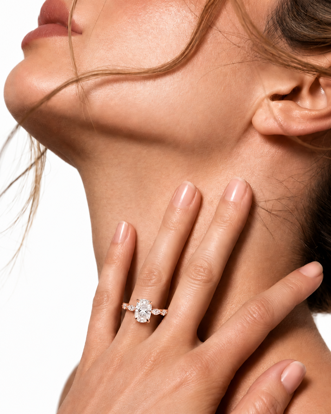 color_10K_RG, color_14K_RG &&A close-up lifestyle shot of a woman's hand and neck wearing a diamond halo ring in a silver-toned band against a clean white background.