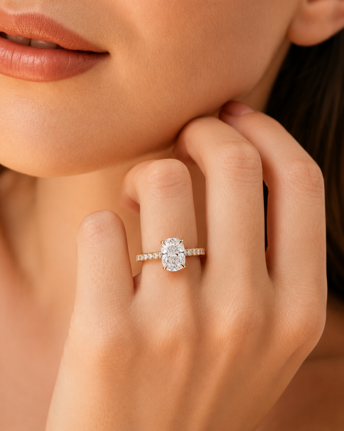 color_10K_YG, color_14K_YG &&A close-up of a woman's hand wearing a diamond engagement ring with a round brilliant-cut center stone and a pave band, shown against her skin.