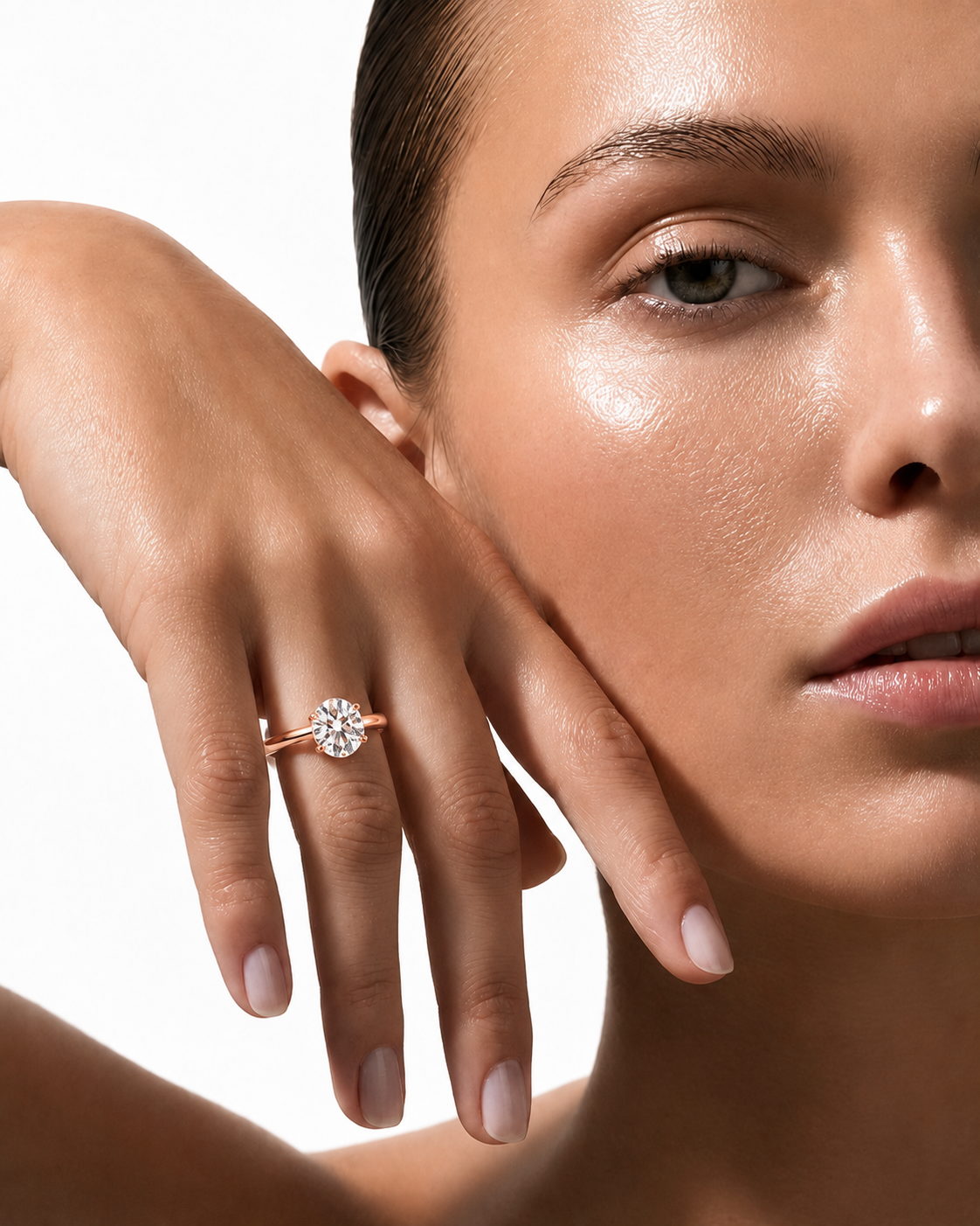 color_10K_RG, color_14K_RG &&A close-up lifestyle shot of a model wearing a rose gold engagement ring with a round-cut clear gemstone on her finger, set against a clean white background.