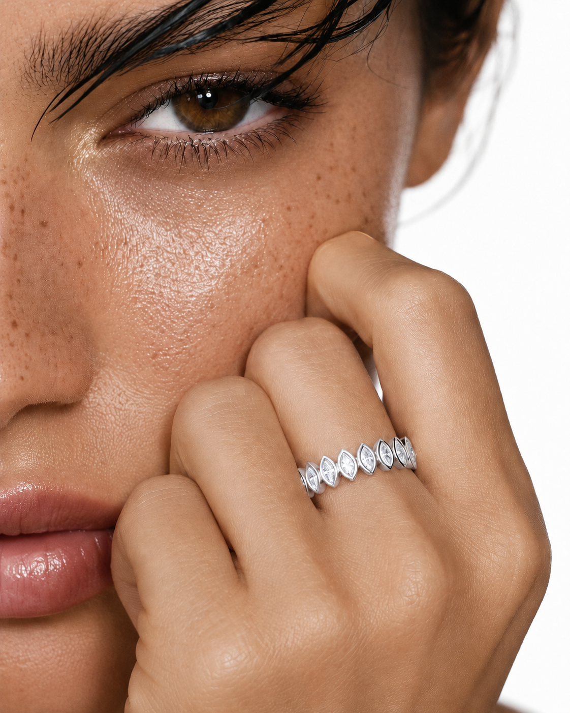 color_925_SIL,color_935_ARG,color_10K_WG, color_14K_WG &&	
A close-up lifestyle shot of a model's face and hand, showcasing a silver marquise-cut diamond eternity band ring on her finger against a clean white background.