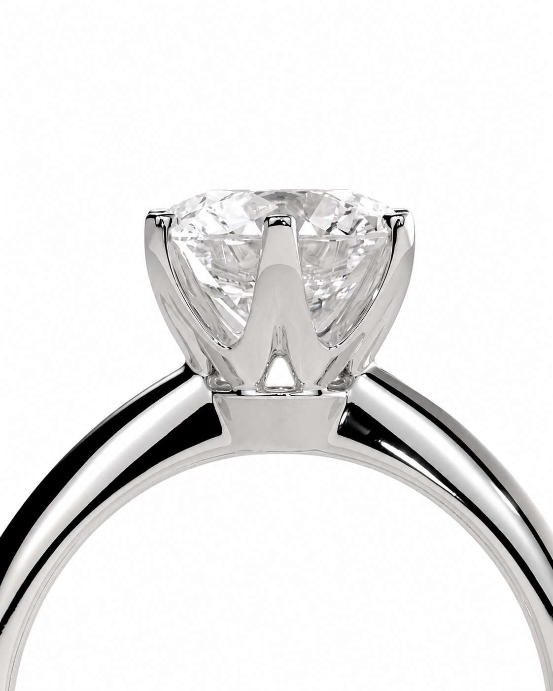 color_925_SIL,color_935_ARG,color_10K_WG, color_14K_WG &&A close-up studio shot of a solitaire engagement ring featuring a round brilliant-cut diamond set in a polished silver-colored metal prong setting, shown against a solid white background.
