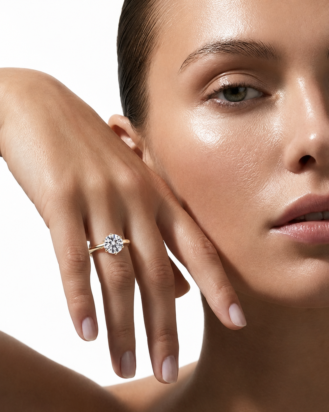 color_10K_YG, color_14K_YG &&A close-up lifestyle shot of a model's hand wearing a classic round-cut diamond engagement ring on a plain white background.