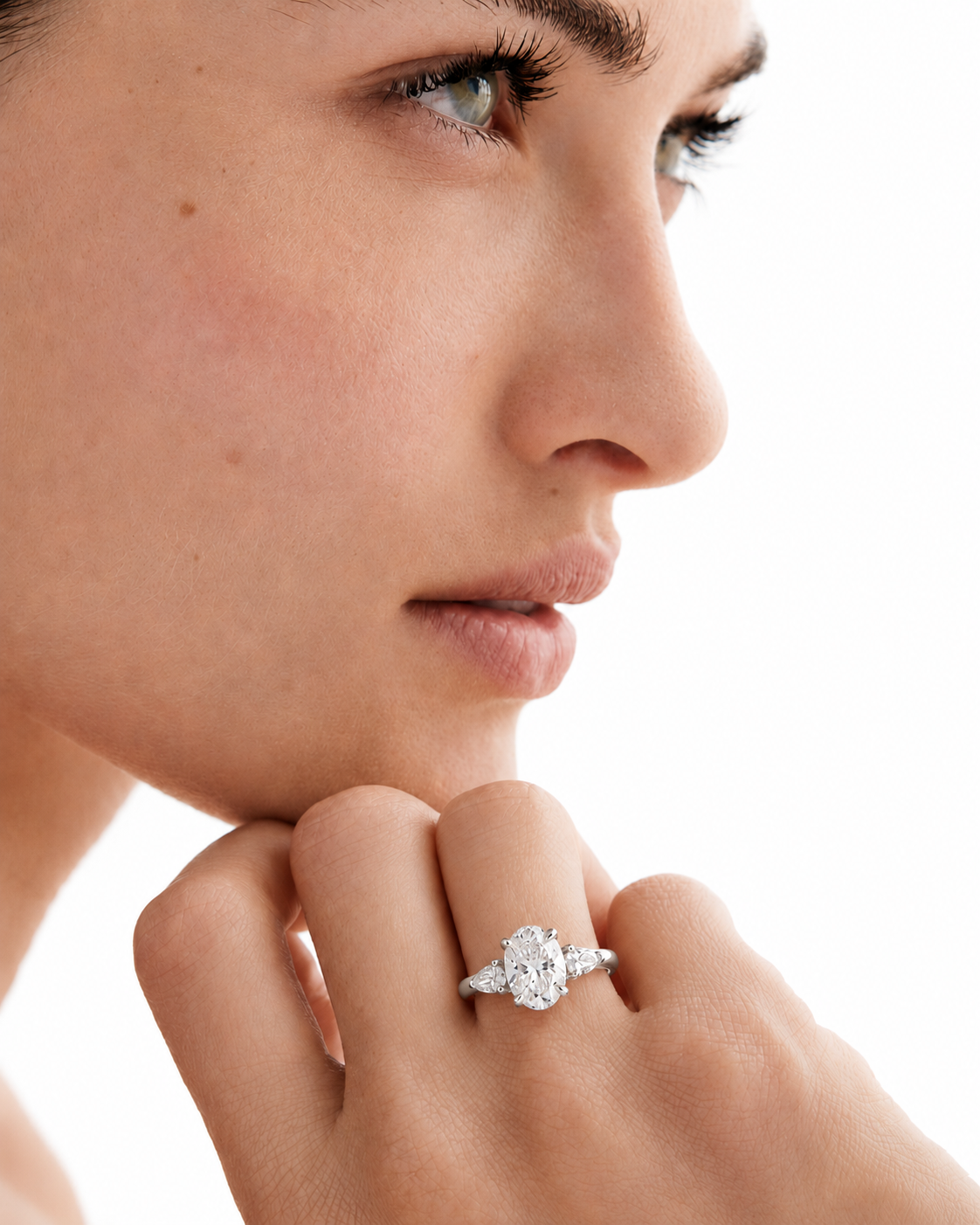 color_925_SIL,color_935_ARG,color_10K_WG, color_14K_WG &&A close-up side profile of a woman wearing a silver-toned ring with a round-cut clear gemstone on her finger, set against a bright white background.