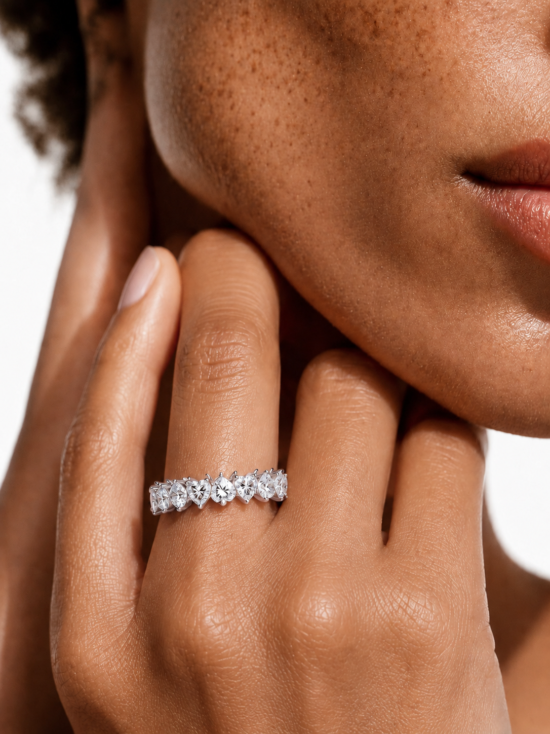 color_925_SIL,color_935_ARG,color_10K_WG, color_14K_WG &&	
A close-up lifestyle shot of a model's hand wearing a sparkling diamond eternity ring. The ring features a continuous line of round-cut diamonds set in a silver-colored metal band.