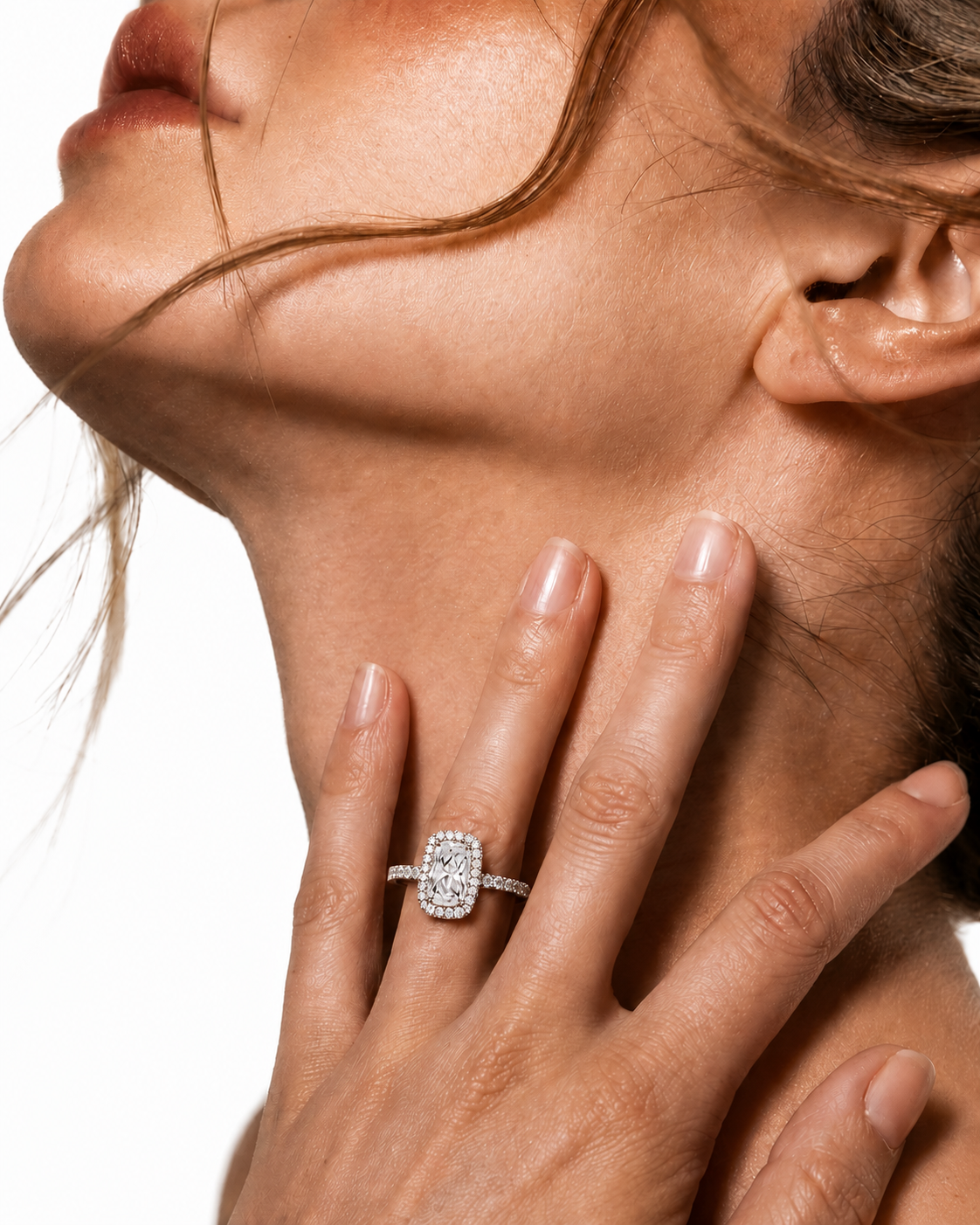 color_925_SIL,color_935_ARG,color_10K_WG, color_14K_WG &&A close-up lifestyle shot of a model wearing a diamond halo ring on her finger, with her hand resting on her neck against a white background.